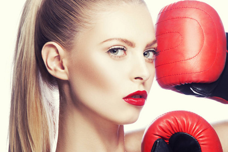 红色嘴唇化妆的年轻妇女和拳击手套在白色背景