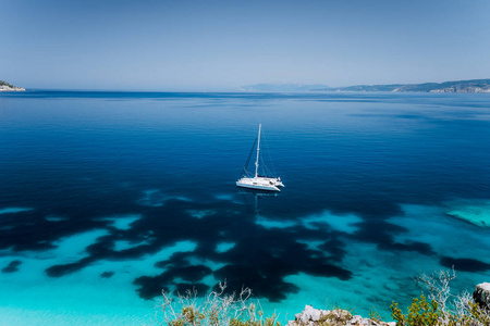 Fteri 海滩, Cephalonia 凯法利尼亚, 希腊。白色双体游艇在清澈的蓝色透明海水表面