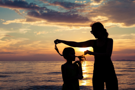 母亲和女儿在日落的时候在海滩上玩
