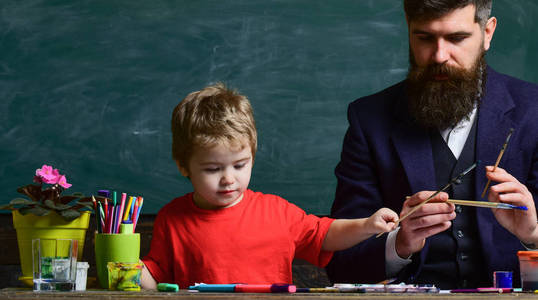 艺术课的概念。老师带着胡子, 父亲教小儿子在教室里画画, 背黑板上的背景。有才华的艺术家花时间和儿子在一起。孩子和老师在繁忙的面