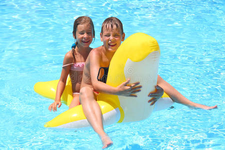 快乐的女孩和男孩在儿童充气玩具旁游泳