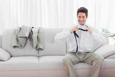 微笑的商人坐在沙发上松开领带