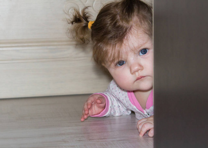 一个小的孩子从衣柜后面偷看。那个长头发的女孩