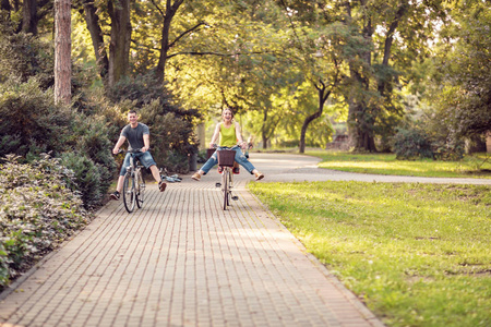 微笑活跃的父亲和母亲与孩子在自行车在公园乐趣。家庭体育与健康生活方式