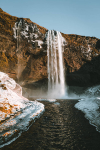 美丽的风景从冰岛的 Seljalandsfoss 瀑布在晴朗的天与蓝色的天空和雪