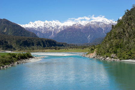 新西兰风光, 山上有雪, 顶上有 turquoises 河, 背景是蓝天。