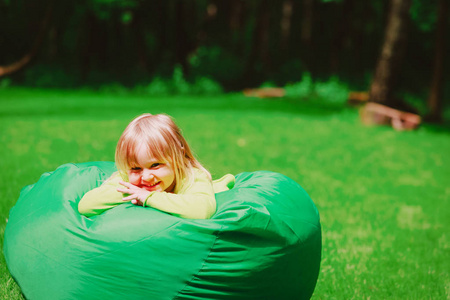 可爱的小女孩在自然的绿色袋子放松