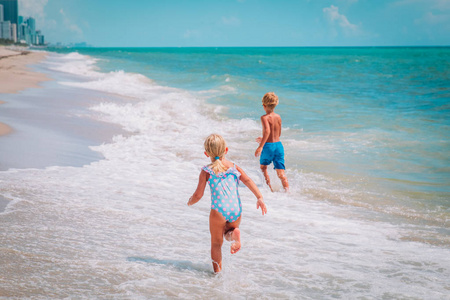 孩子女孩和男孩奔跑在海滩波浪戏剧