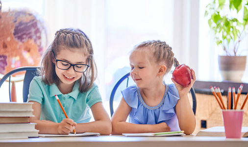 回学校去快乐可爱的勤劳的孩子们坐在室内的书桌旁。孩子们在课堂上学习