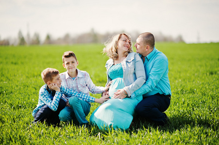 幸福的怀孕家庭，两个儿子穿着绿松石的凝块