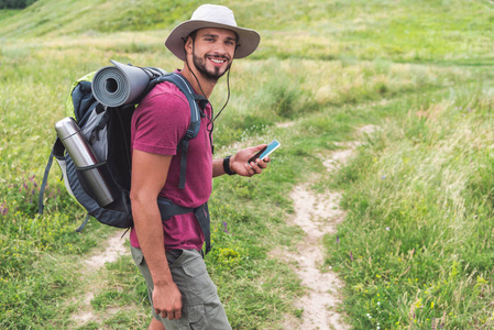 旅行者与背包使用智能手机在夏天草甸
