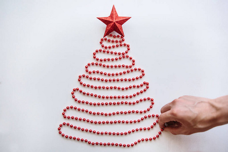 一个人创造一个创造性的圣诞或新年树由珠子制成的简约风格和装饰与明星