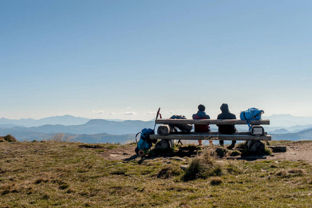 一张桌子上的山顶和两个游客谁坐在他身后, 看着远处的山脉