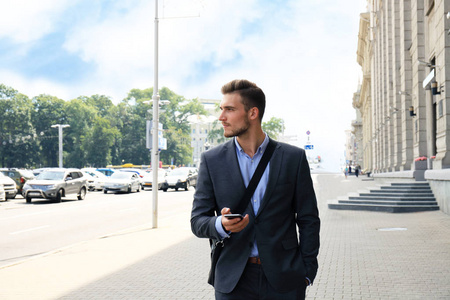 年轻的城市商人专业上走在街道使用手机的智能手机