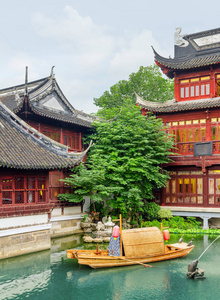 中国传统的木制小船和池塘的风景景观, 在旧城市上海的黑色弧形屋顶的建筑物之间。上海是亚洲最受欢迎的旅游胜地。