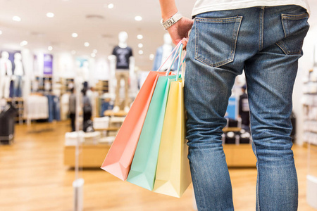 聪明的人拿着五颜六色的购物纸袋在手工购物后, 在百货公司的服装店在夏季节日销售, 购物生活方式和布料或时尚的概念
