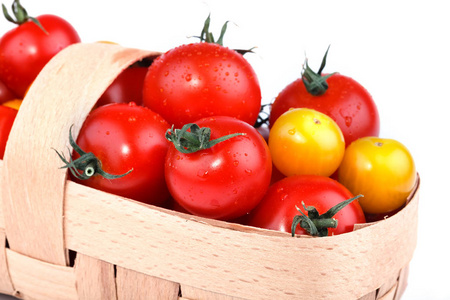 黄色和红色的西红柿躺在白色背景上的篮子里