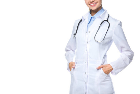 裁剪视图的微笑的医生摆在白色大衣与听诊器, 孤立的白色