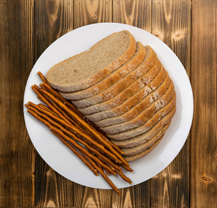 木桌上白色盘子上的褐色面包片。照片来自上方或顶端视图