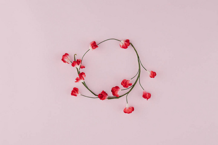 红色纸花的圆花圈与枝在粉红色背景与拷贝空间