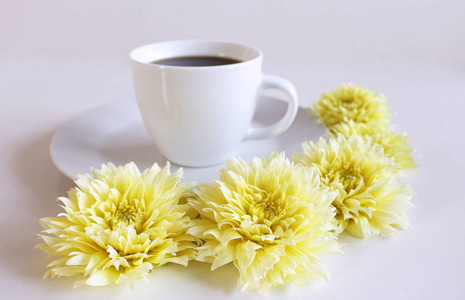 桌上有一杯黑咖啡和一朵黄色的大丽花花。背景模糊