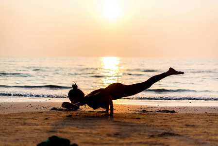 ung frisk kvinna utvar yoga p stranden vid solnedgngen