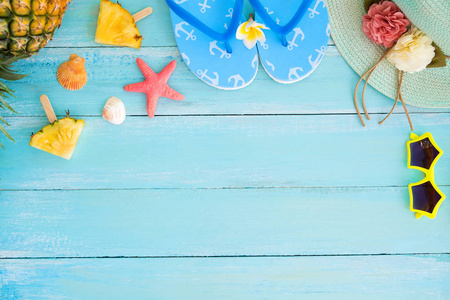 假日概念。菠萝片, 贝壳, 海星, 拖鞋, 草帽和太阳镜在木板蓝色的颜色。暑假背景概念。顶部视图