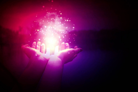 在一个女人的手掌上的魔术粒子在一个黑暗的, 紫色的背景。神奇的粒子, 闪光的光, 能量的流动