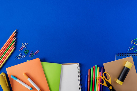 蓝色背景下的空教科书和各种文具的顶部视图