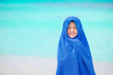 在海边游泳后在热带海滩裹着浴巾的可爱的小女孩