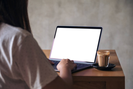 在木桌上使用带有咖啡杯的空白白色桌面屏幕的笔记本电脑的图像