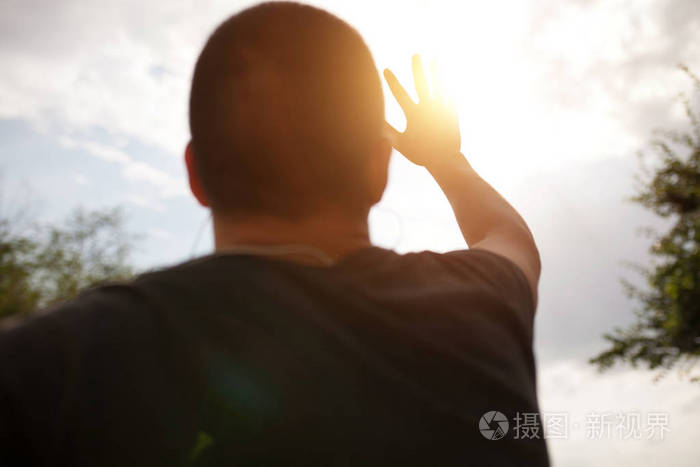 一只手伸向天空, 遮住太阳, 太阳的光芒穿过手, 特写