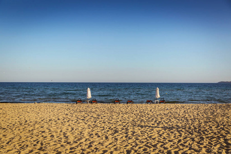 海滩与日光浴在风景如画的蓝色海海湾的背景下。晚间时间