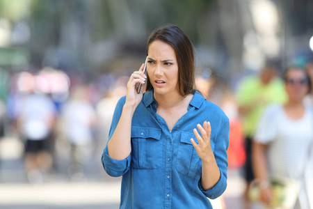 在街上打电话的愤怒的女人的前视图肖像