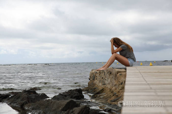 全身轮廓画像一个沮丧的女孩抱怨坐在海滩上