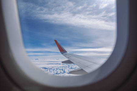 飞机机翼和蓝天在多云的一天通过窗口