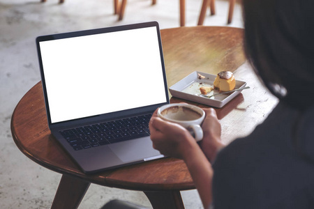 在咖啡馆里喝热咖啡的时候, 一个女人用空白的白色桌面屏幕看笔记本电脑的图像