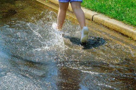 快乐的女孩在雨天奔跑和跳跃在水坑中雨后夏季显示水滴