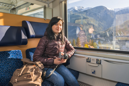 坐在高山铁路火车旅行。年轻女子乘火车坐在窗前拿着相机的手