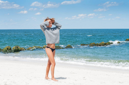 穿着比基尼的快乐棕褐色的女人在热带海滩上享受海边漫步