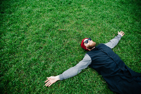时髦男孩戴著墨镜，躺在草地上
