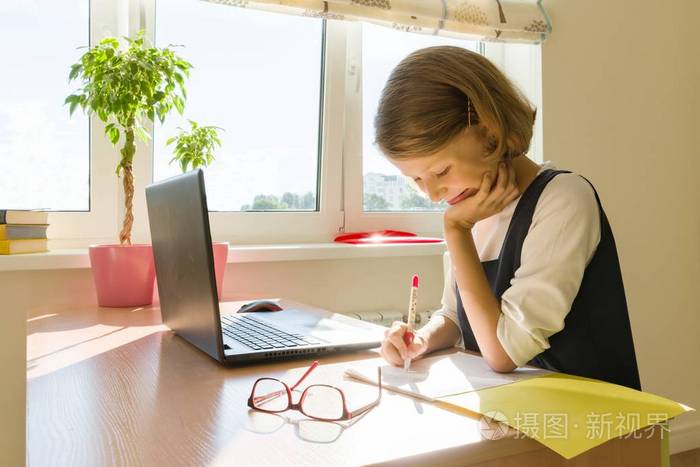 女学生, 8 岁的女孩, 坐在桌子上看书, 在笔记本上写字.