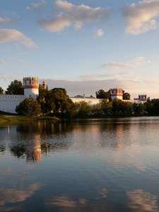 莫斯科的新修道院的墙壁和塔在夏天傍晚日落反射在水里