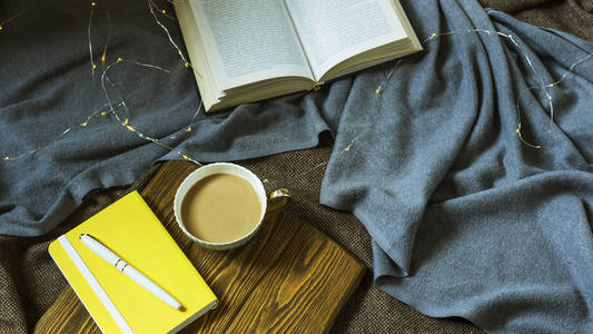 一杯咖啡和一个记事本在木制的立场为 plihaad。在冬季或秋季舒适的家庭环境中工作和休息