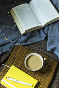 一杯咖啡和一个记事本在木制的立场为 plihaad。在冬季或秋季舒适的家庭环境中工作和休息