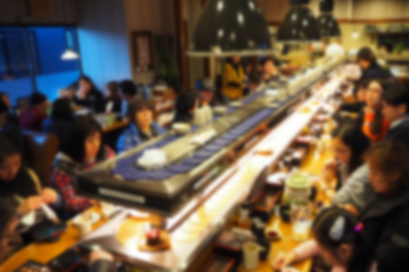 在日本餐馆吃寿司传送带的人模糊的抽象背景