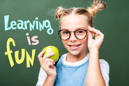 学童拿着苹果和触摸眼镜靠近黑板, 用 学习是乐趣 字样