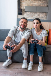 已婚夫妇与游戏板一起玩电子游戏, 而坐在沙发上在家