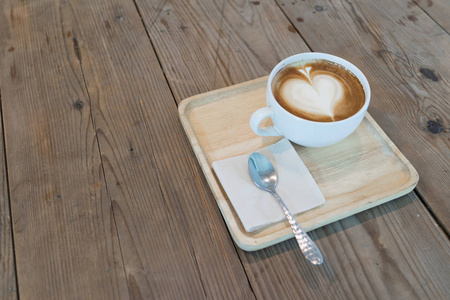 热卡布奇诺咖啡，餐巾和勺子木制的桌子上