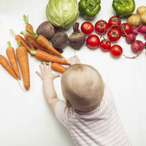 小宝宝伸手到新鲜的有机蔬菜上的轻木背景。关心健康。健康的婴儿食品。平躺, 顶部视图